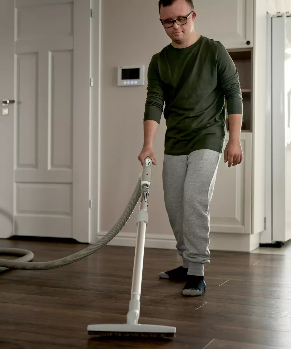 Boy with down syndrome vacuuming floor in home