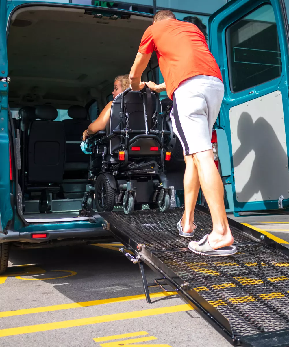 Man pushing woman in wheelchair into van