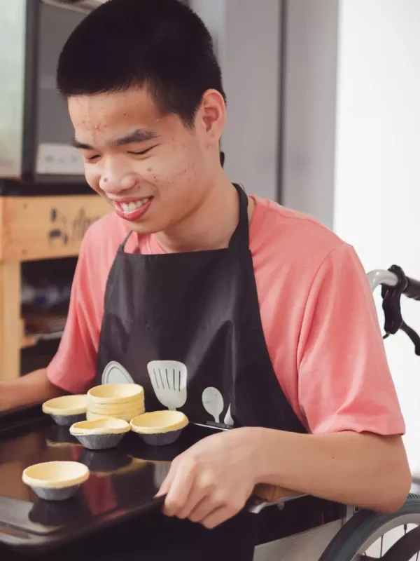 Disabled boy in wheelchair cooking pastries in kitchen